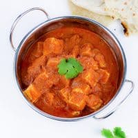 tofu cubes in makhani sauce served into an Indian-style dish decorated fresh coriander leaves and naan bread