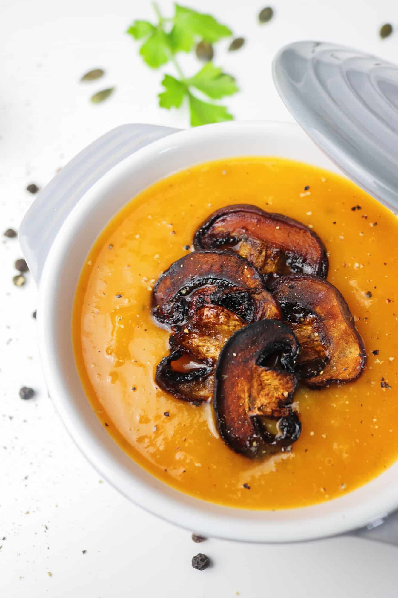 This roasted pumpkin soup with mushroom "bacon" bits close up on a single pot