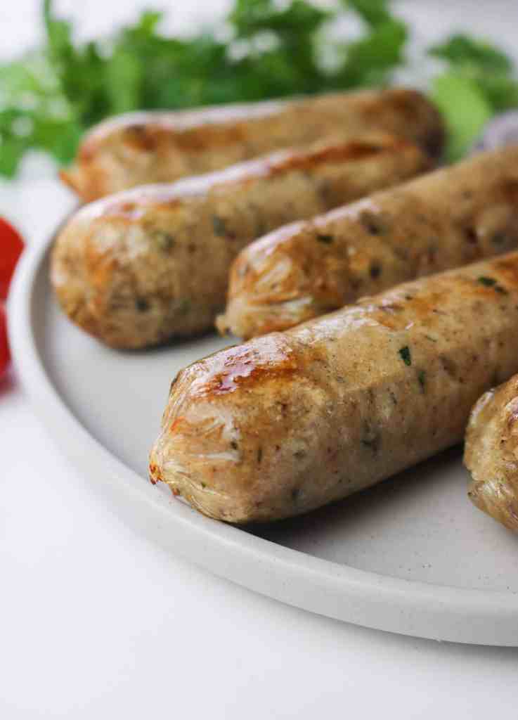 homemade vegan italian sausages with gluten and hummus roasted on a plate close up