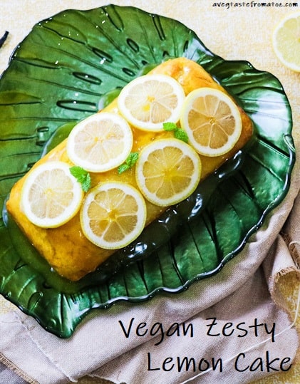 Lemon cake loaf on a green plate leaf shaped topped with lemon slices and mint