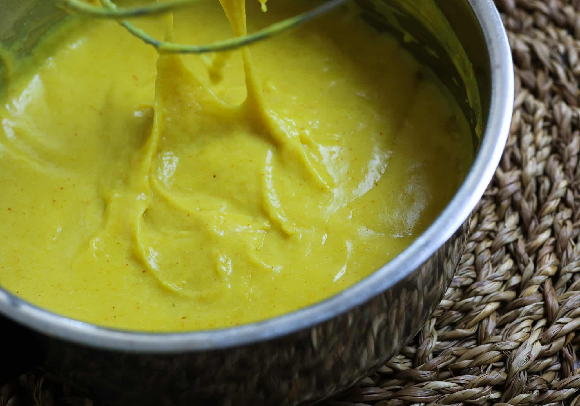 detail of turmeric cheese sauce with whisk stretching it
