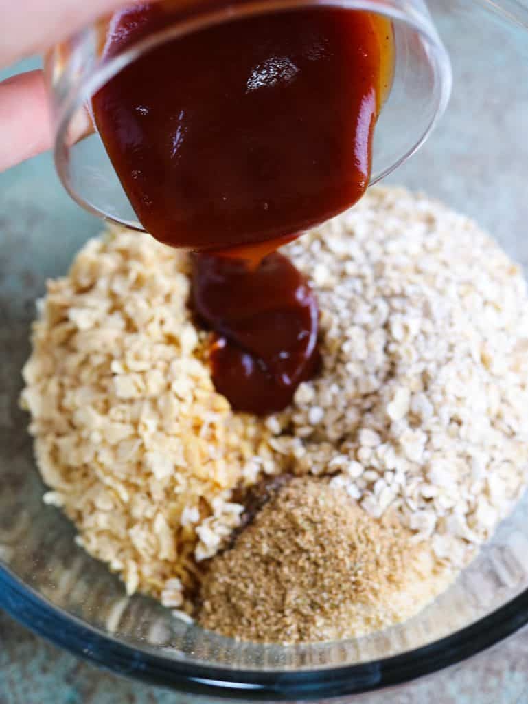 poring barbecue sauce over vegan burger mixture