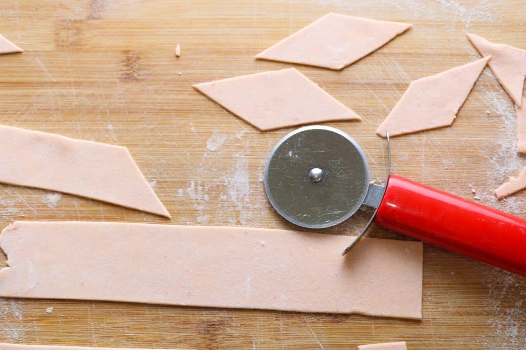cutting red lentil pasta maltagliati with red pizza cutter