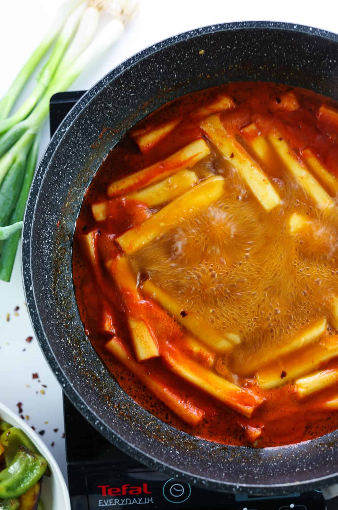 softening the rice cakes in a black wok with spicy red sauce