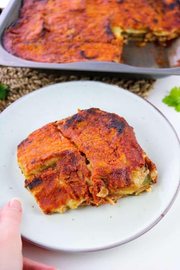 hand holding a portion of vegan courgette parmigiana