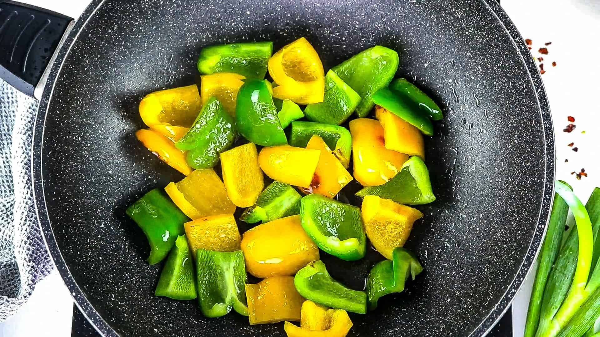 sautéed green and yellow capsicum in a black wok