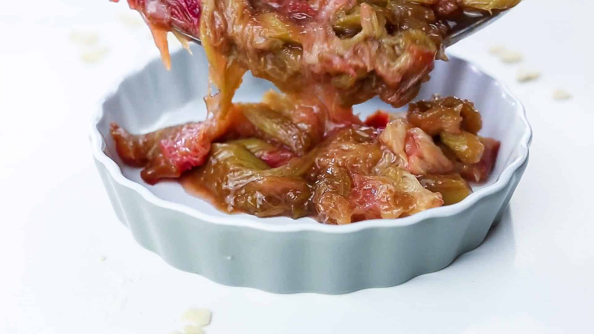 pouring cooked rhubarb in ceramic plate to be cooked in the oven