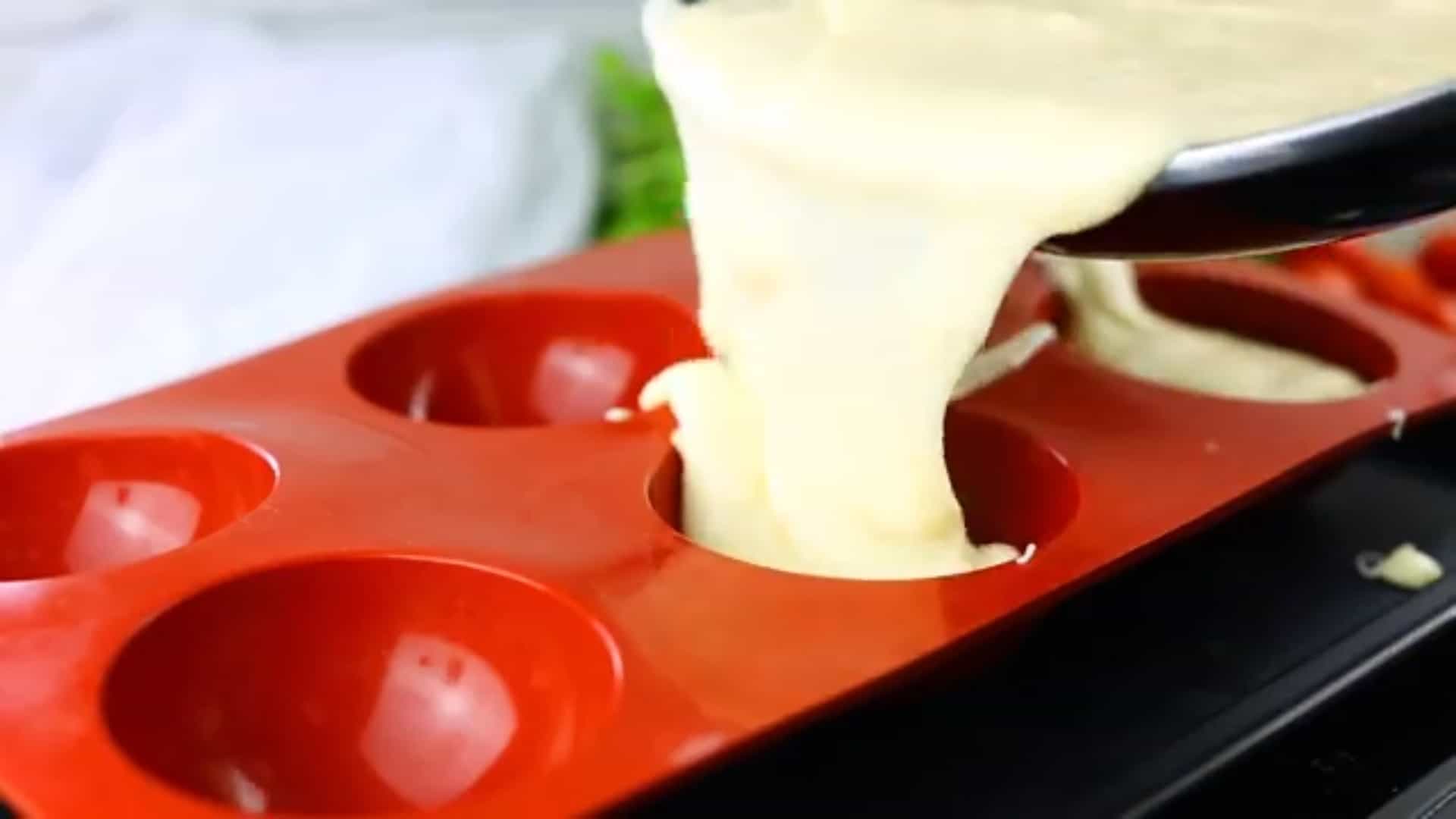 poring mozzarella mixture into a red silicon mold semi sphere shaped