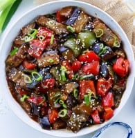 Vegan Aubergine & Peppers in Black Bean Sauce in a white bowl topped with green onions and sesame seeds
