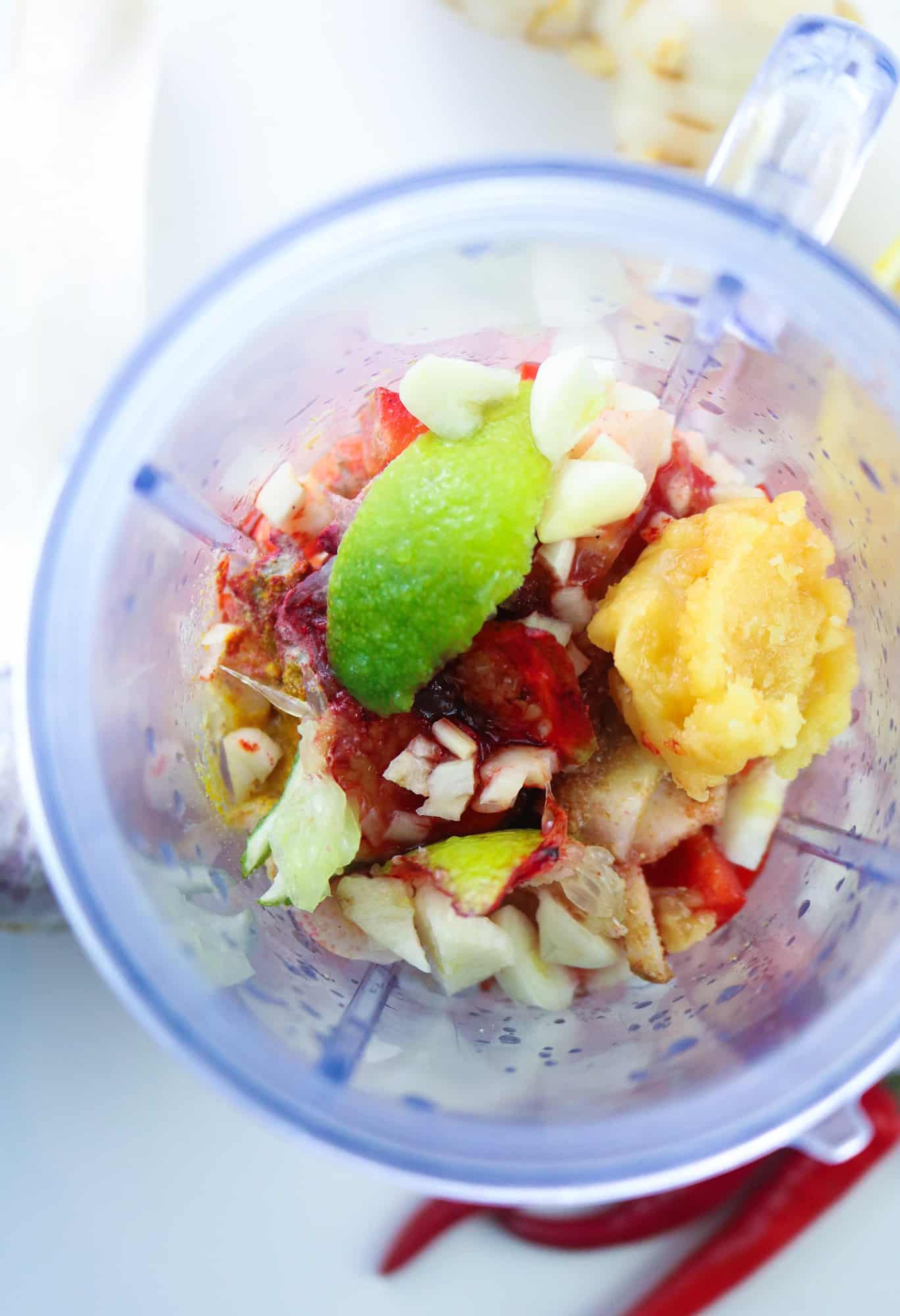 ingredients to prepare Vegan Thai Red Curry Paste roughly chopped and placed inside a plastic blender glass