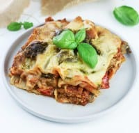 slice of creamy veggie lasagna with pesto and mozzarella sauce topped with basil leaves