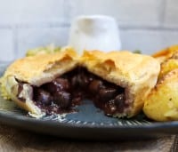 Mushrooms & Shallots Vegan Pie in a rich Red Wine Gravy cut in half on a plate showing inside