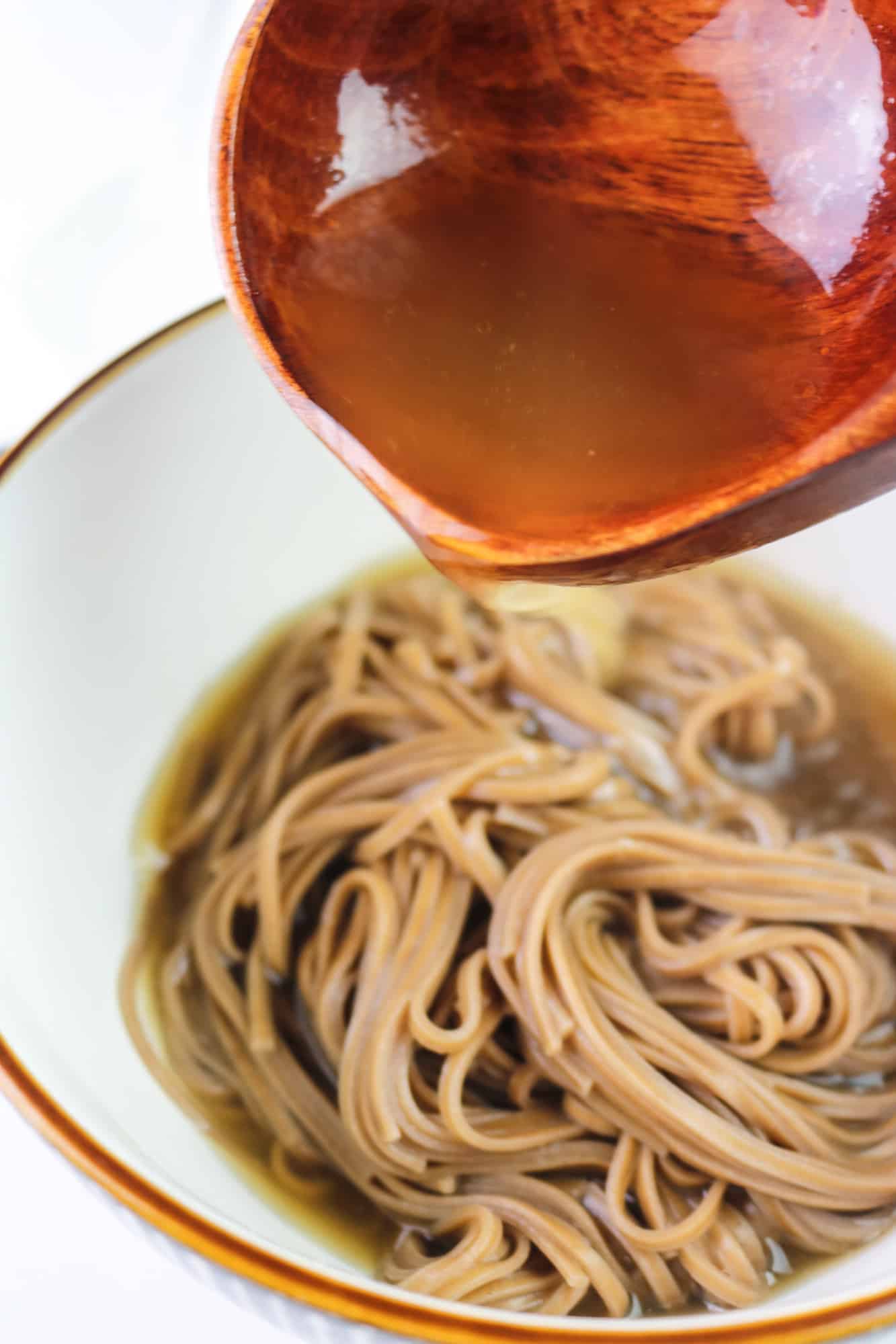 pouring broth over noodles