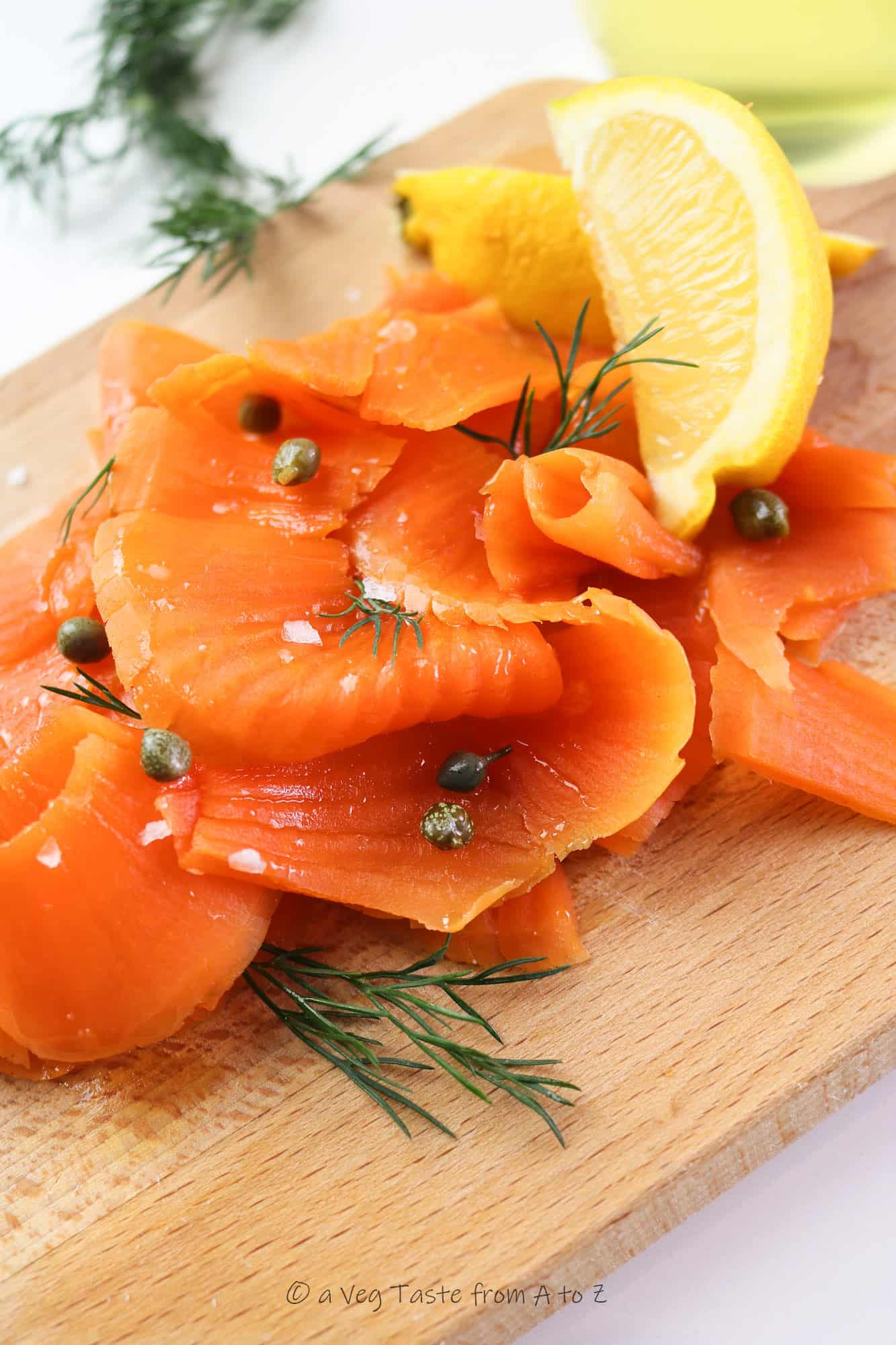 best vegan salmon / carrot lox close up on a wooden tray with lemon wedges, capers and dill