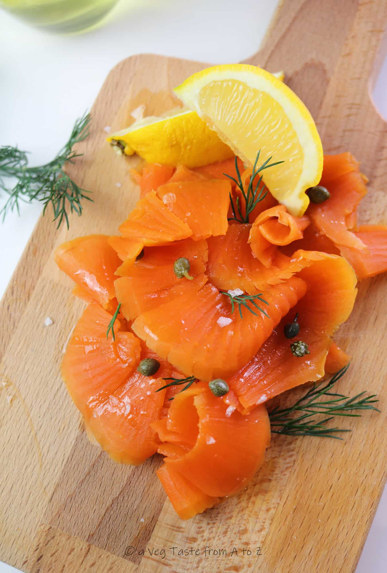 best vegan salmon / carrot lox close up on a wooden tray with lemon wedges, capers and dill