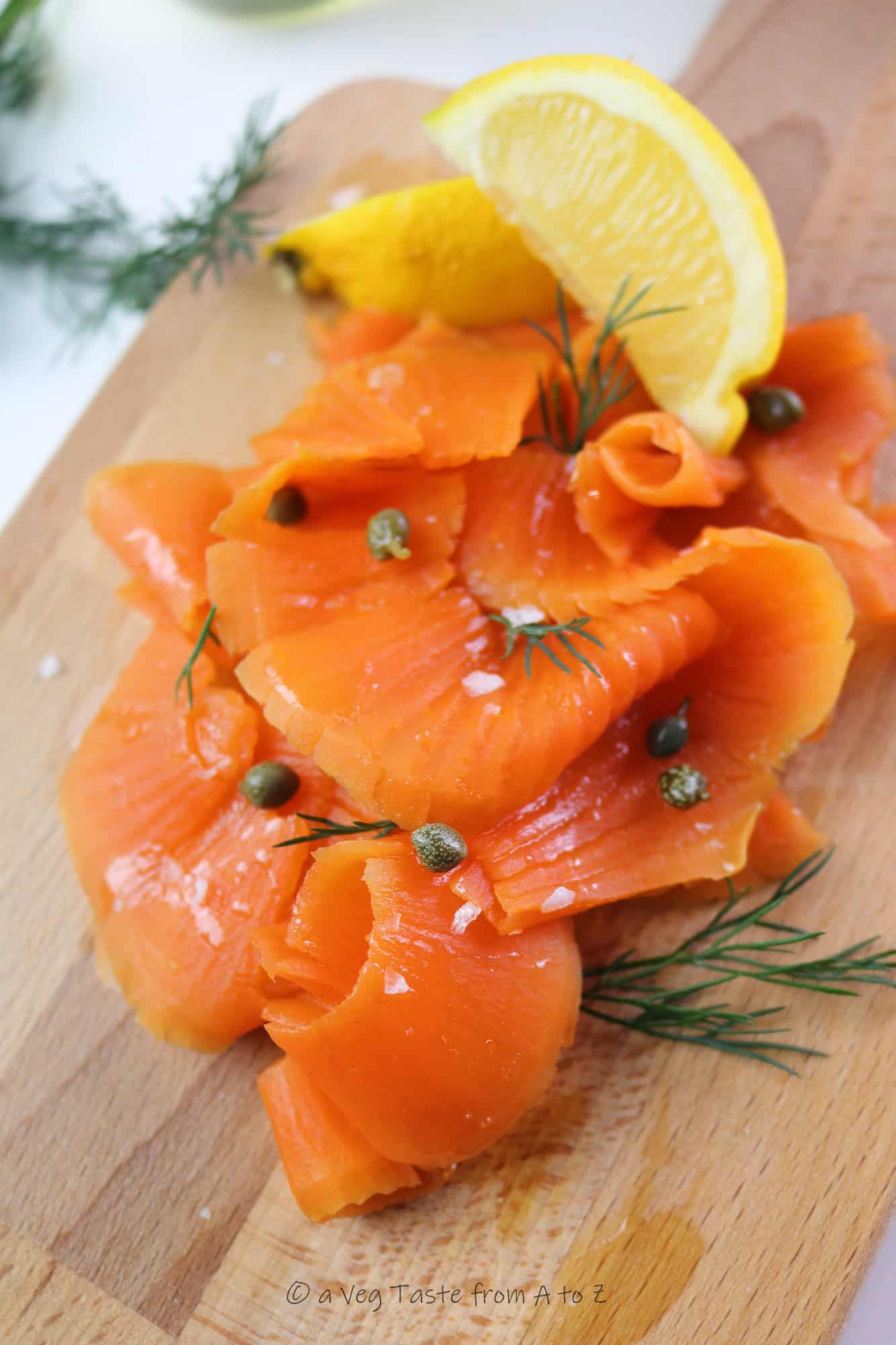 best vegan salmon / carrot lox close up on a wooden tray with lemon wedges, capers and dill