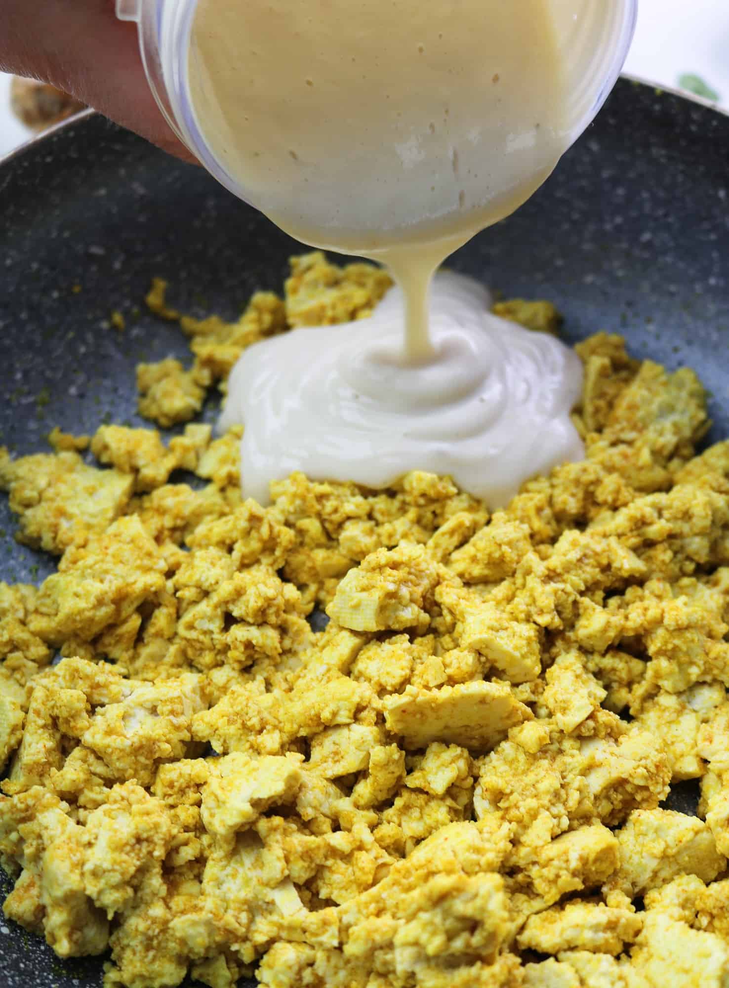 pouring silken tofu mixture on scrambled tofu