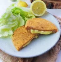 cordon bleu cut in half with oozy filling on a plate with salad and lemon