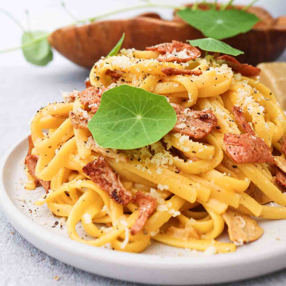 linguine carbonara on white plate with decorative leaves