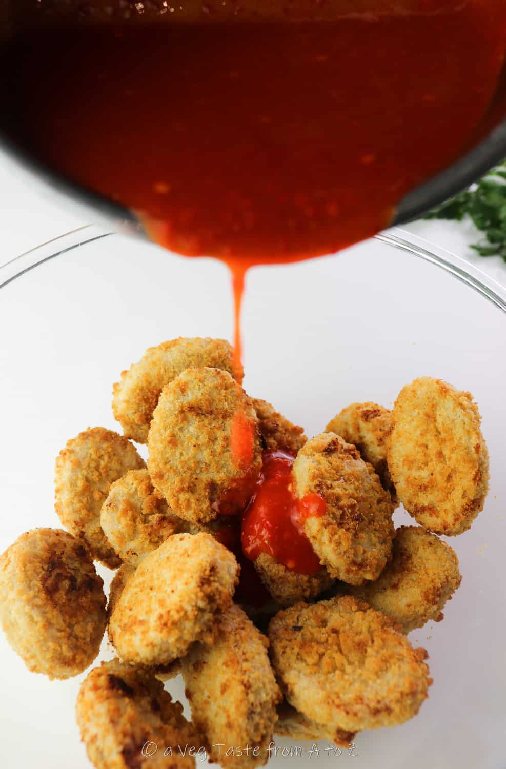 pouring homemade hot sauce on vegan nuggets