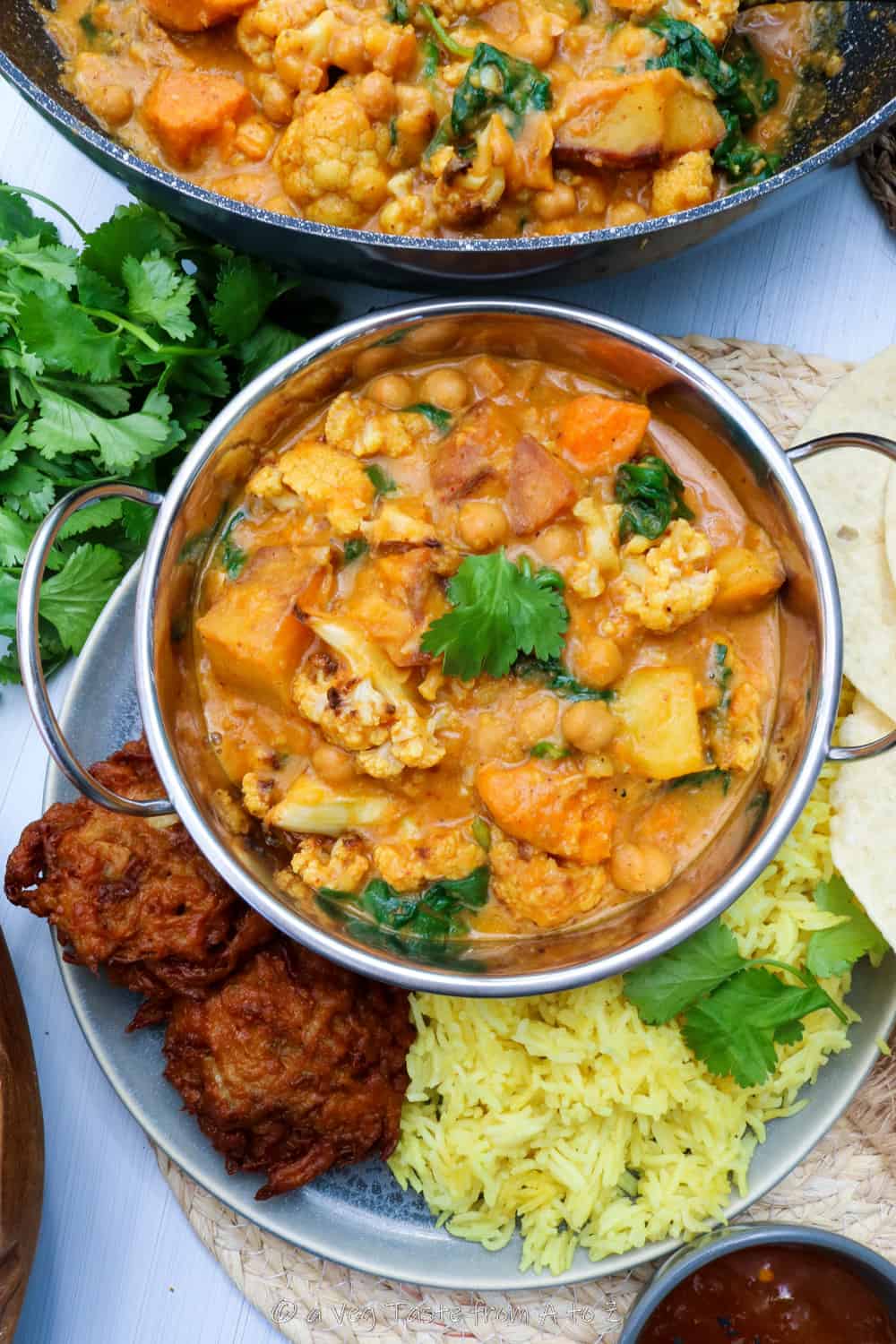 Mangalorean Roasted Cauliflower Curry plated in a traditional Indian bowl with pakoras and fresh herbs