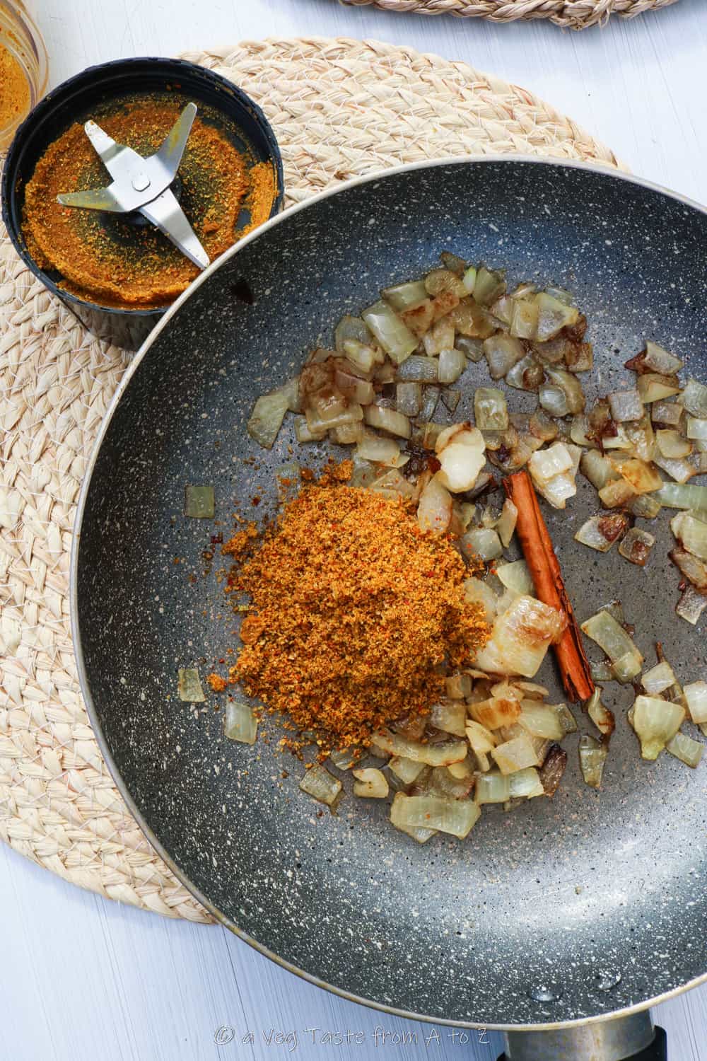 Blended spice mix, cinnamon stick and sautรฉd onions in a wok