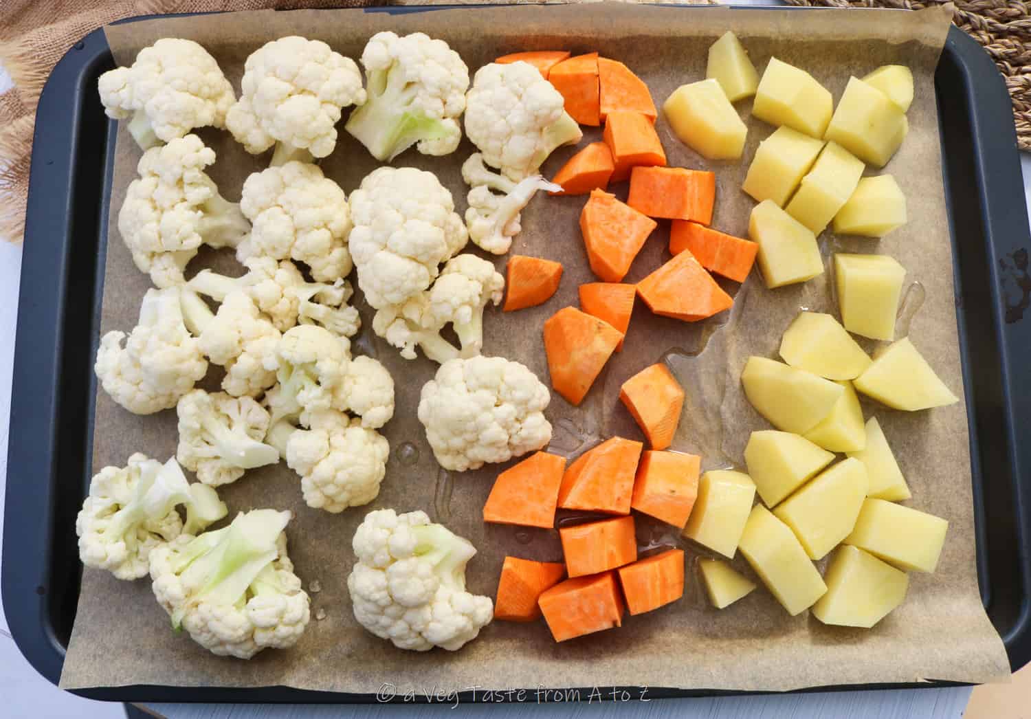 cauliflower florets, diced onions and carrots on a sheet tray ready for the oven