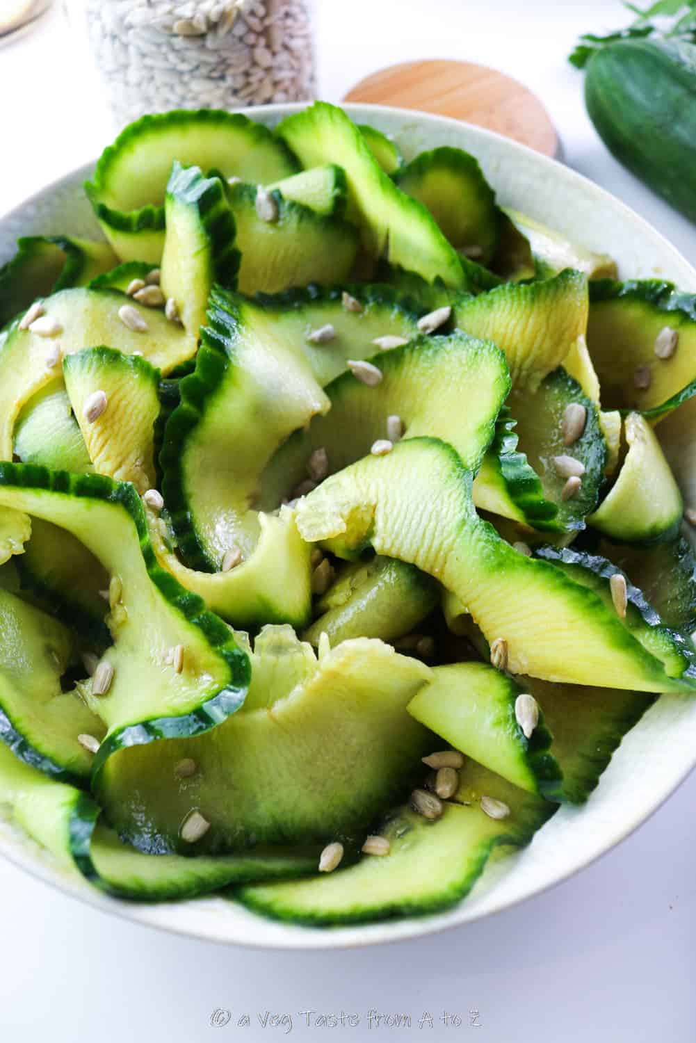 close up to spiralized cucumber in a plate with dressing and sunflower seeds