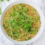risi e bisi in a white plate topped with pea shoots