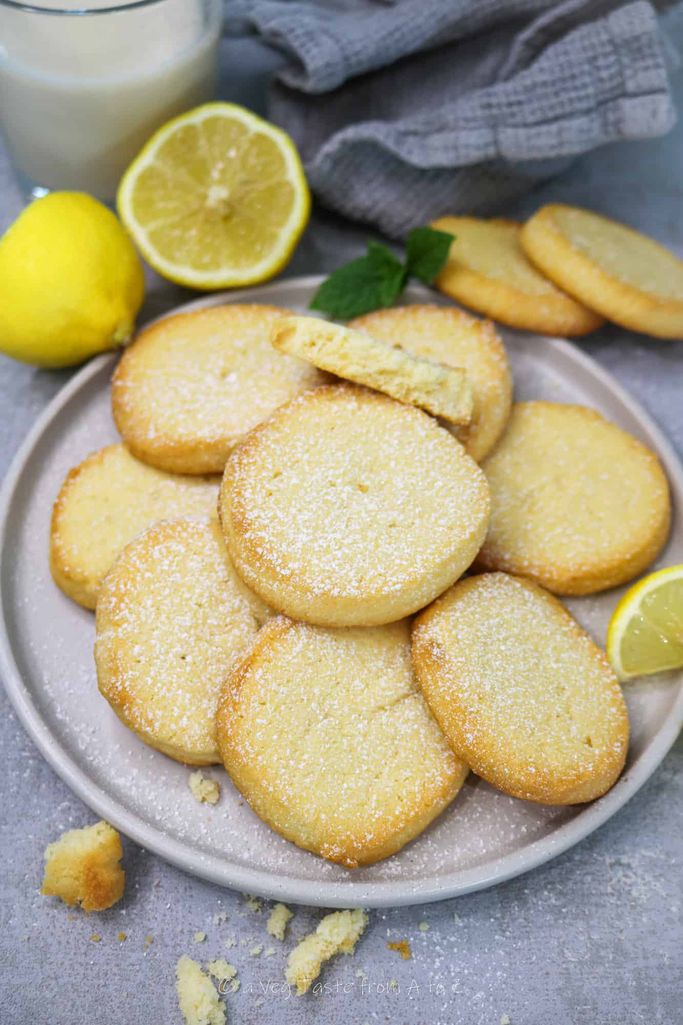 vegan lemon cookies on a plate with icing sugar