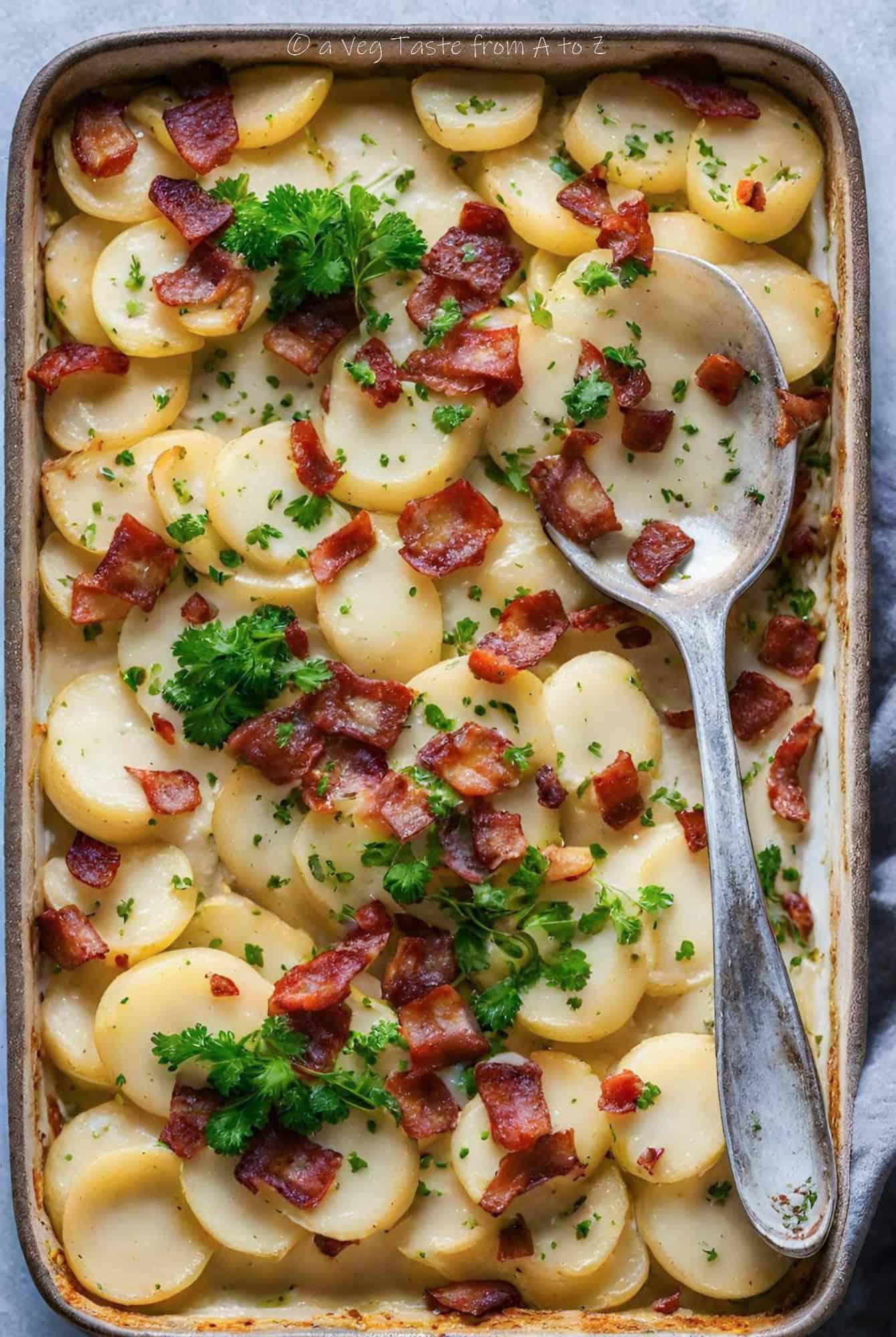 creamy scallopped potatoes with crispy vegan bacon in a tray with fresh parsley and spoon
