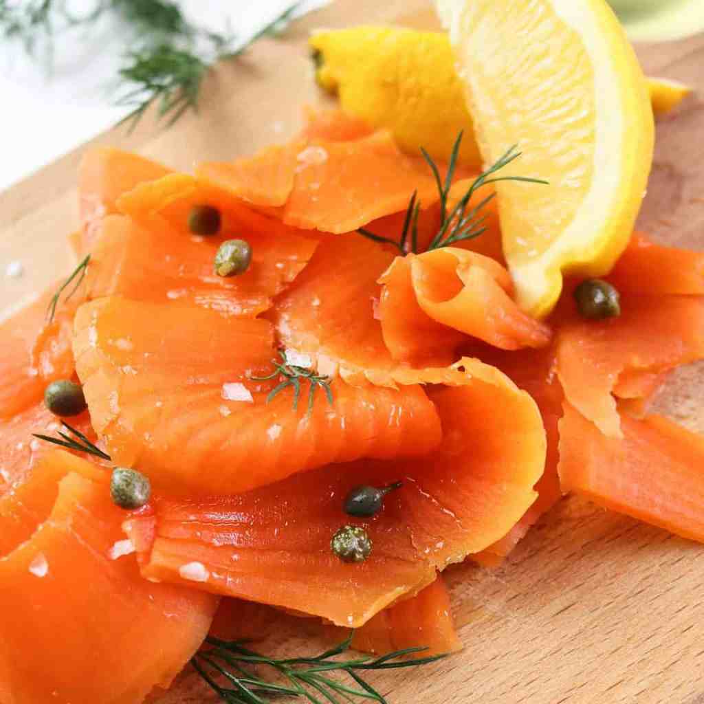 best vegan salmon / carrot lox close up on a wooden tray with lemon wedges, capers and dill