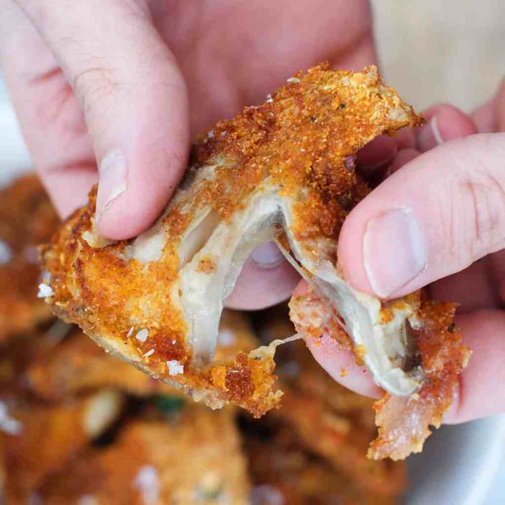 tearing with hands a breaded and air fried oyster mushroom