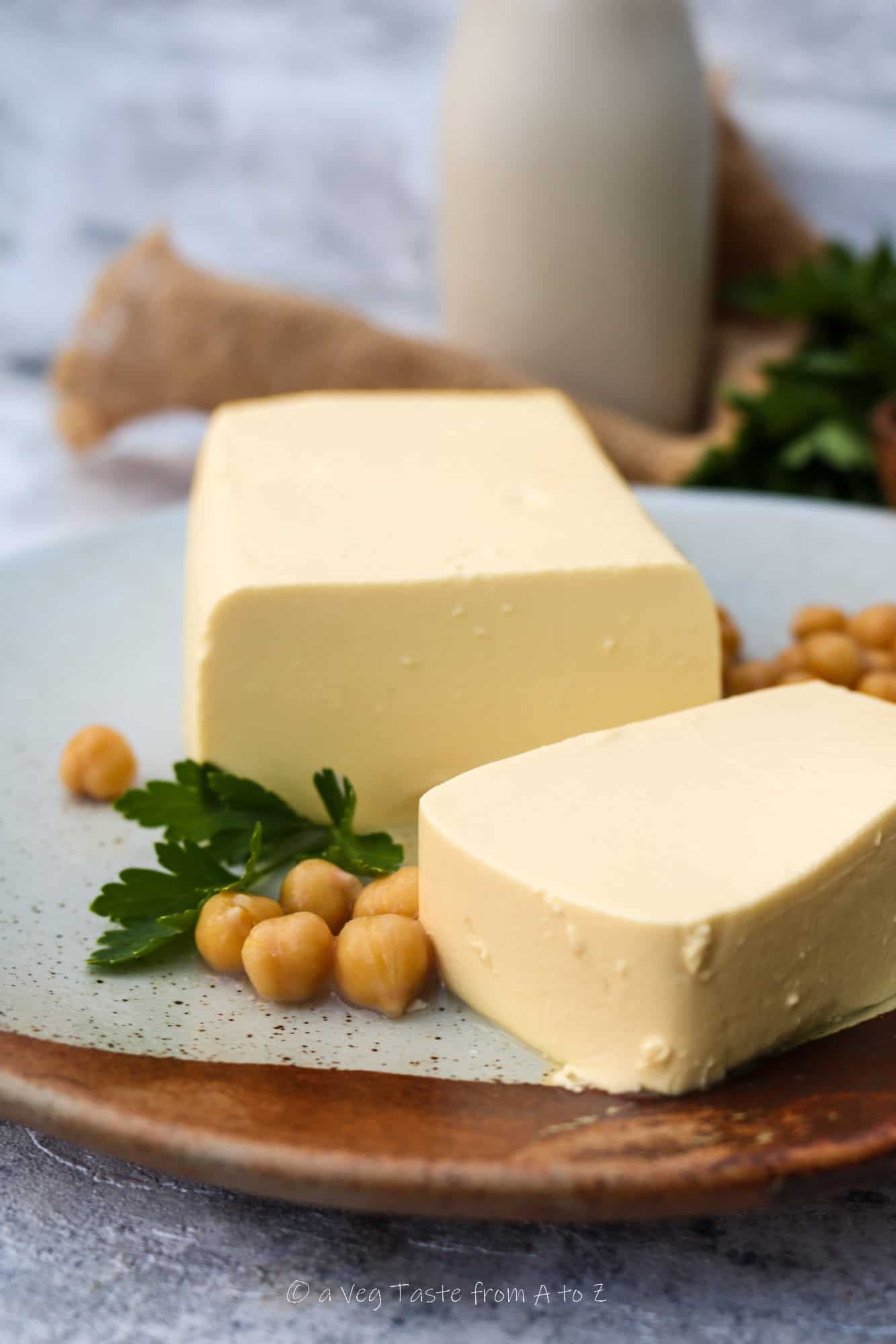 burmese chickpea tofu block close up on a plate with decorative chickpeas and herbs