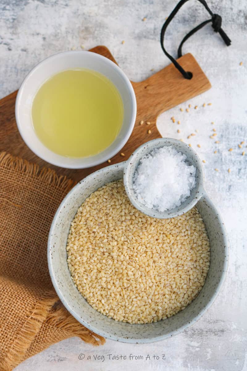 pot with vegetable oil, pot with sesame seeds and small pot with salt on a wooden chopping board