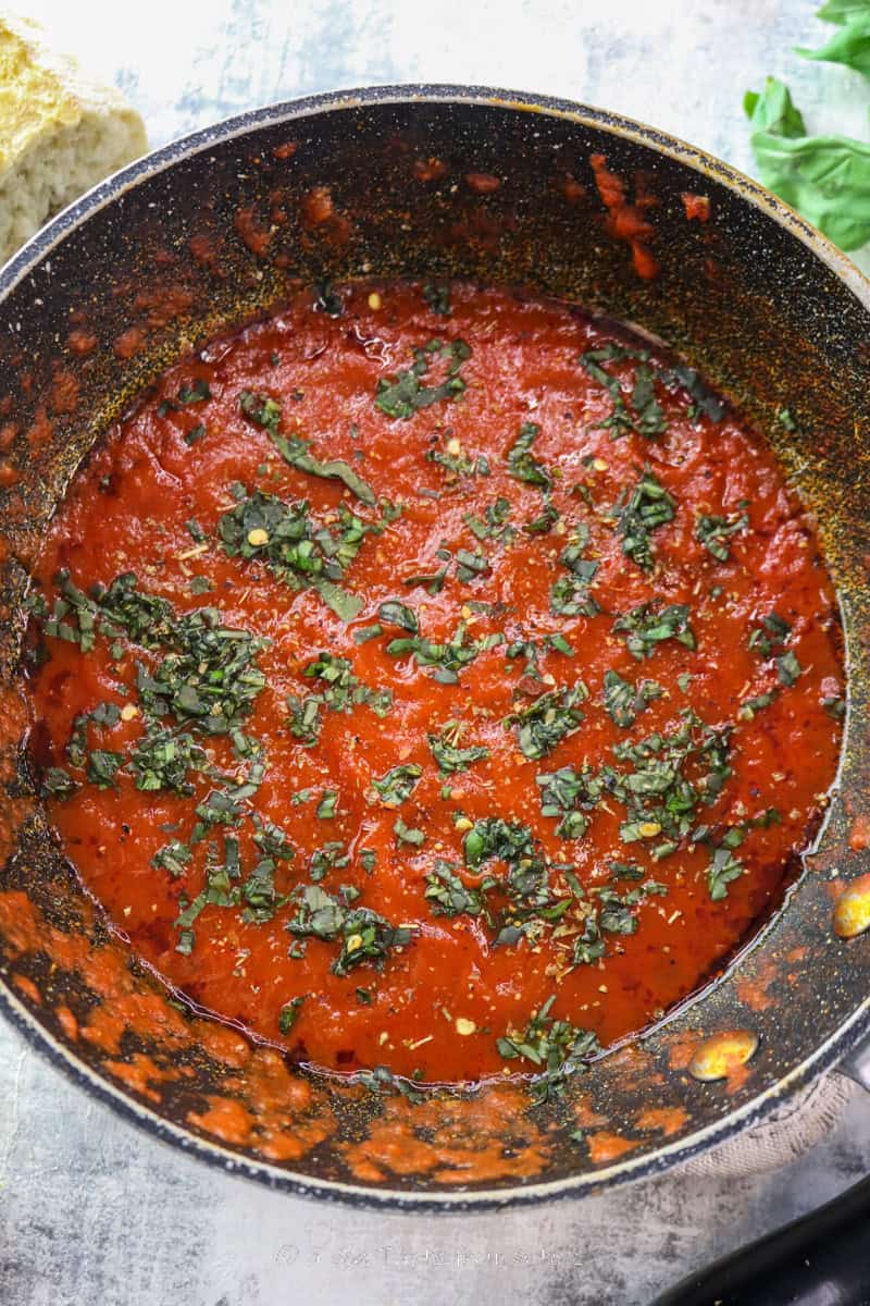 marinara sauce still in its cooking pan topped with fresh basil