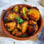 patatas bravas tapas in a ceramic bowl topped with fresh parsley