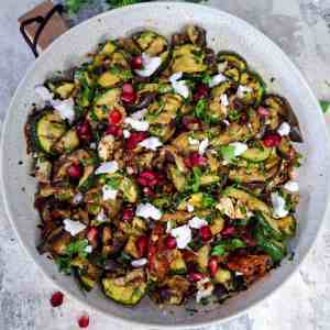 vibrant and healthy Mediterranean grilled veggie salad, loaded with charred aubergines, courgettes, vegan feta, sundried tomatoes, and pomegranate seeds.